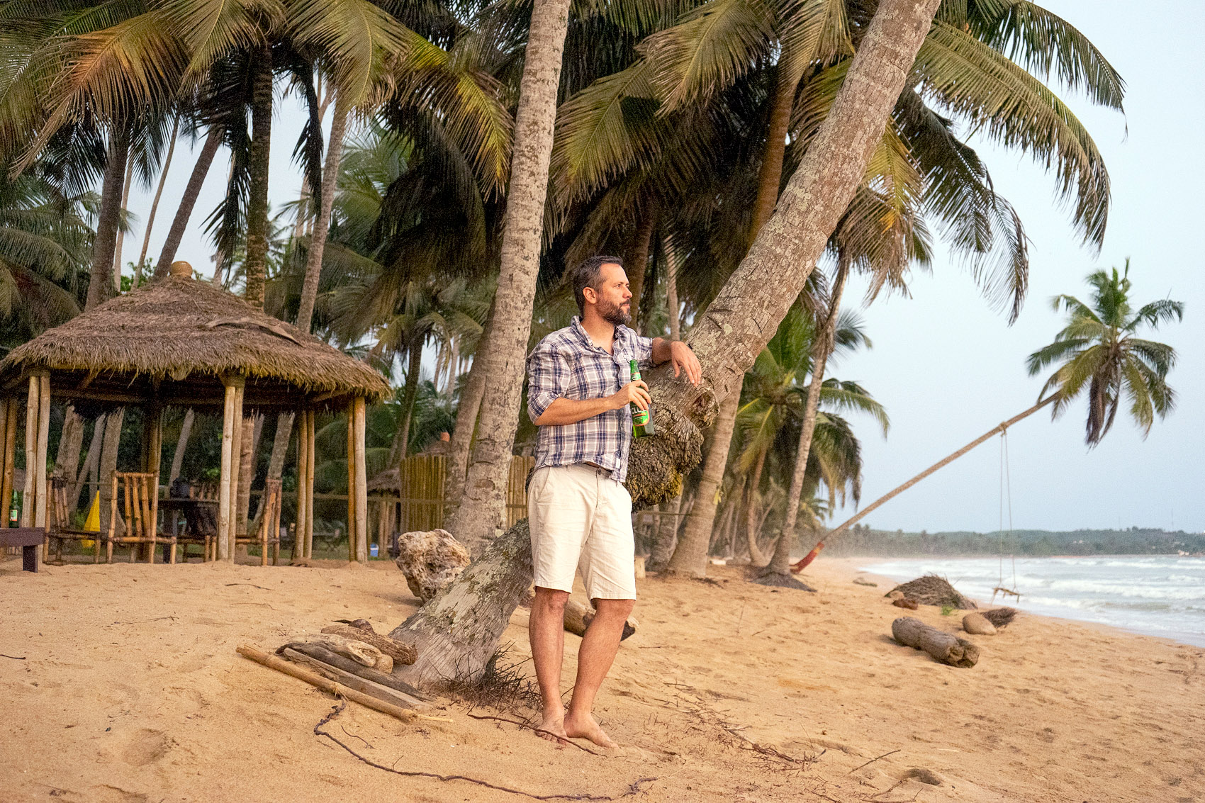 Mann trinkt ein Bier an einem Traumstrand in Ghana